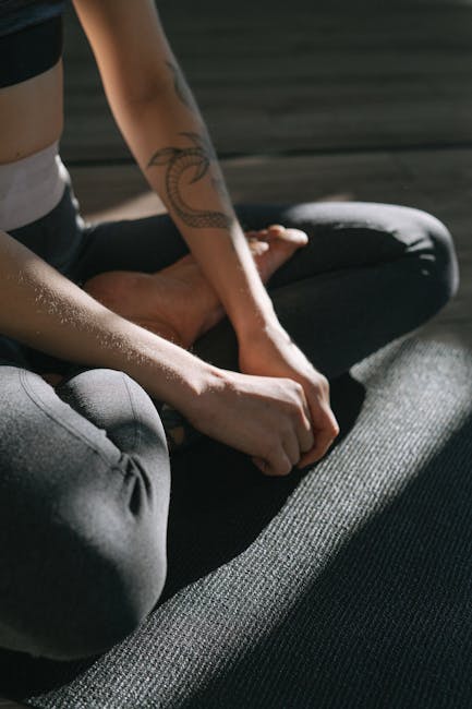 A person sitting in a comfortable cross-legged pose on a yoga mat